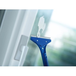 Grattoir pour fenêtres et sols LUX en cours d'utilisation pour enlever des résidus de peinture sur une vitre.