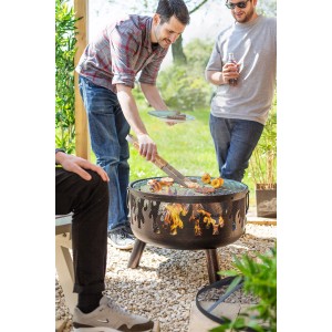 Brasero Buschbeck Wildfire avec fonction grill en utilisation avec des personnes faisant des grillades.