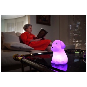 Veilleuse Starlyf Cushy Light chien, violette, sur table. Femme lit dans le salon. 7 couleurs, tactile.