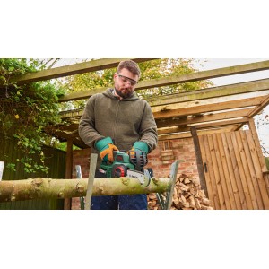 Homme sciant du bois avec une tronçonneuse à batterie Bosch UniversalChain 18. Tronçonneuse à batterie compacte pour le jardinage.