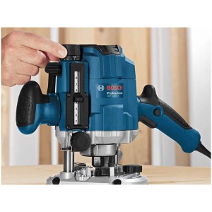 Défonceuse Bosch Professional GOF 1250 CE bleue avec main ajustant la profondeur de fraisage.