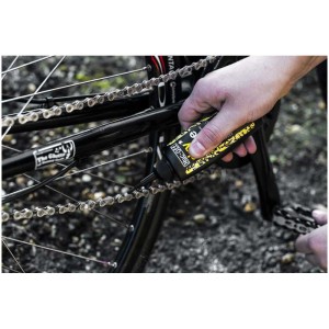 Application de l'huile de chaîne Muc-Off Dry Lube sur une chaîne de vélo pour une lubrification et un entretien optimal.