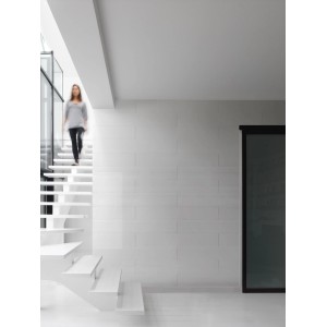 Pièce lumineuse avec revêtement mural blanc Grosfillex et escalier.
