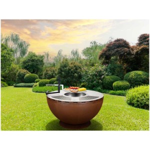 Brasero-grill Nouvel Firebowl 100 en tôle rouillée avec des aliments grillés dans le jardin.