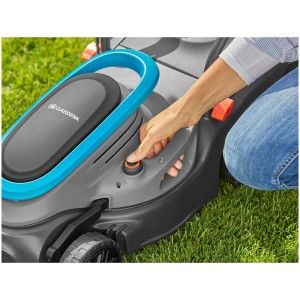 Gardena PowerMax 32 tosaerba elettrico in azione: mano che avvia il tosaerba sull'erba.