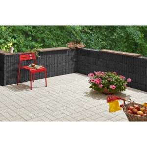 Mini blocchi da piantare antracite come muro di giardino e bordo con sedia rossa e fiori.