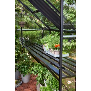 Tavolo a lamelle nero Halls Qube 68 in serra con piante.
