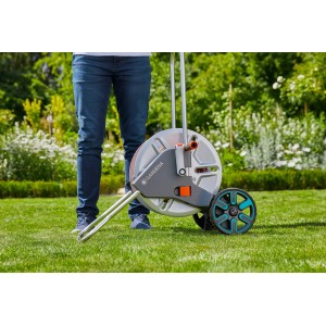 Gardena CleverRoll M Metal avvolgitubo con persona su prato. Carrello avvolgitubo da giardino con tamburo in metallo e ruote.