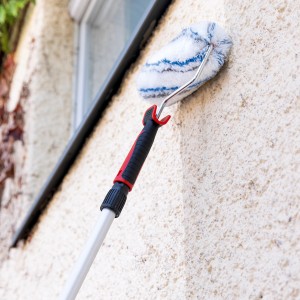 Kit de peinture avec manche télescopique en utilisation : rouleau peignant un mur clair et texturé. Idéal pour la rénovation.