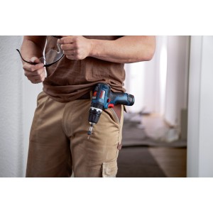 Avvitatore a percussione a batteria Bosch Professional GSB 12V-35 sulla cintura, con occhiali di protezione in mano.