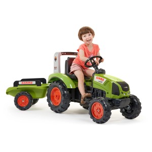 Trattore verde Falk Claas con rimorchio, bambino seduto al volante sorridente.