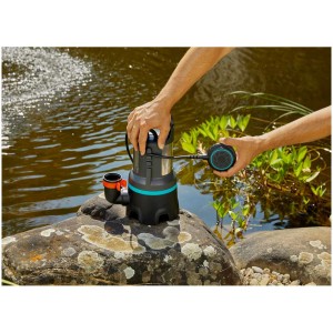 Pompe submersible eaux chargées Gardena 16000 l en utilisation près d'un bassin, avec boîtier en acier inoxydable et interrupteur à flotteur.