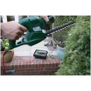 Boîte de câble noire Dribox IP55 taille M utilisée avec un taille-haie dans le jardin.