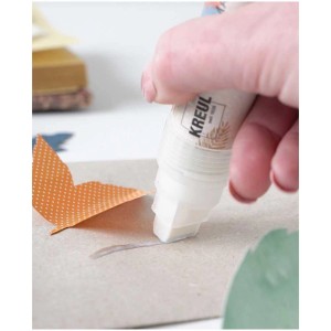 Kreul Klebemarker Stift in Anwendung: Hand klebt Papier mit Flüssigkleber für Bastelarbeiten.