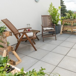 Lastre da pavimentazione grigie 30x30 cm con smusso posate su una terrazza con mobili da giardino.