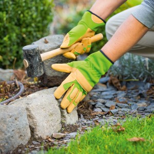 Guanti da giardino verdi taglia 10 usati per pavimentare con un martello.