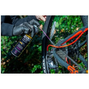 Application du spray chaîne PTFE Muc-Off sur une chaîne de vélo pour conditions sèches.
