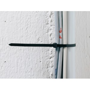 Collier de serrage blanc OBI (290x4,6 mm) regroupant des câbles sur un mur.