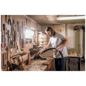 Homme utilisant l'aspirateur eau et poussière Kärcher WD 6 pour nettoyer des copeaux de bois sur un établi.