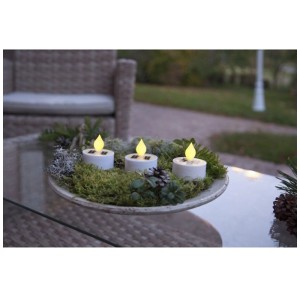 3 bougies solaires LED blanches Star Trading sur table avec décoration. Extérieur.