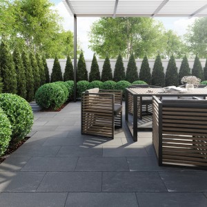 Terrazza con lastre per pavimentazione in pietra naturale Lima Black scura (30x60). Mobili da giardino e piante verdi.