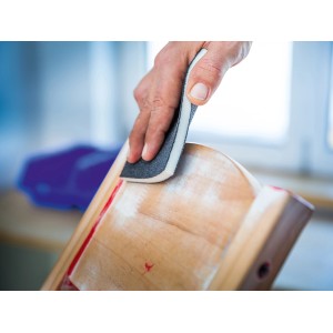Mano che leviga il legno con set di spugne abrasive LUX. Abrasivi per superfici in legno.