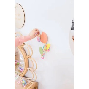 Un enfant accroche des bijoux du kit de fabrication de bijoux Bijoux Box Trendy Multi Beads à une décoration murale.