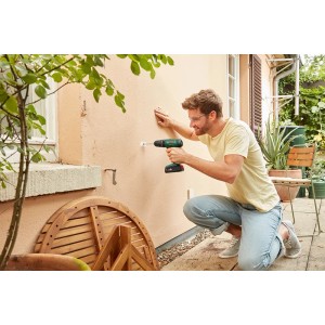 Uomo che fora un muro con trapano avvitatore a percussione a batteria Bosch 18V. Include batteria e valigetta.