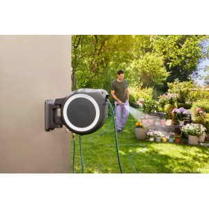 Gardena Avvolgitubo a parete RollUp M/L con tubo da giardino e lancia a spruzzo in uso.