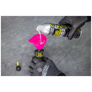 Muc-Off Dry Lube Schmiermittel wird in kleine Flasche mit Trichter umgefüllt.
