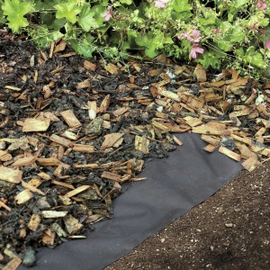 Telo pacciamante nero Windhager Anti Weed sotto pacciame in giardino.