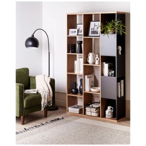Grande bibliothèque Beliani Bangor, marron-noir, avec 14 compartiments, remplie de livres et de déco dans un salon moderne.
