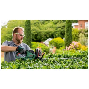 Tagliasiepi elettrica Bosch UniversalHedgeCut 60 in uso per tagliare una siepe.