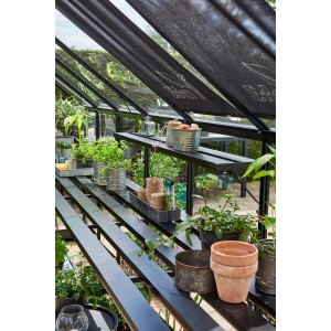 Étagère Halls Qube, noire, 138 cm, dans une serre avec des plantes et accessoires.