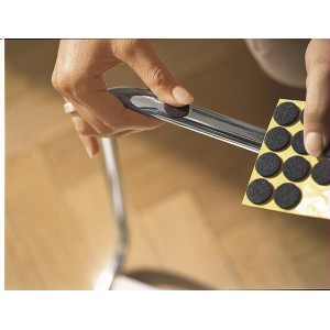 Des patins en feutre Tesa bruns et ronds (22 mm) sont fixés à un pied de chaise.