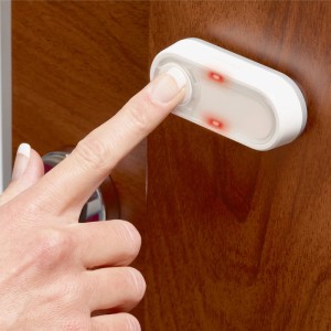 Main appuyant sur le bouton de sonnette sans fil Honeywell DCP511 avec LED sur porte en bois.