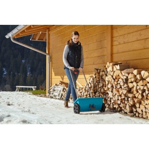 Donna che usa lo spargitore Gardena L per spargere materiale antigelo in inverno.