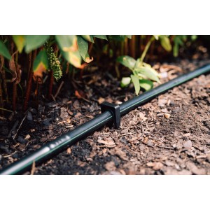 Geka Drip Rohrhalter Erdspieß (10 Stk.) fixiert ein schwarzes Tropfrohr im Gartenboden.