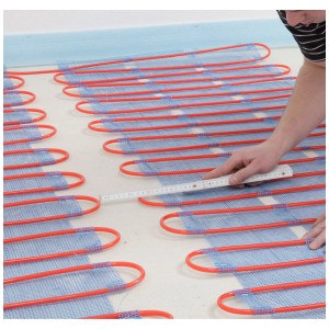 Chauffage au sol Perobe (5m²) avec tuyaux rouges sur natte bleue, posé sur surface claire.