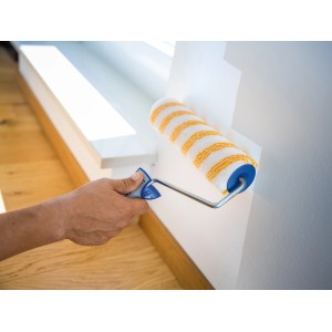 Rullo a dispersione LUX 25cm in azione: Pittura di una parete con rullo a strisce giallo-bianco.