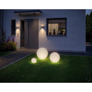 Tre luci LED Paulmann Globe illuminate in un giardino di fronte a una casa. Luce bianca calda.