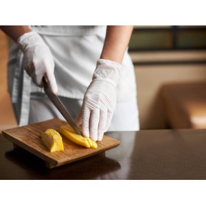 Scena: Persona taglia mango con guanti monouso bianchi senza lattice taglia L su tagliere di legno.