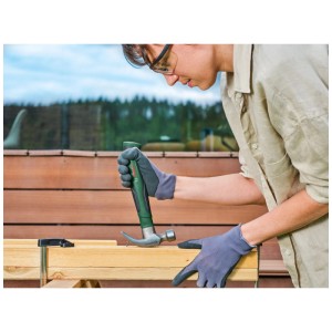Marteau de charpentier Bosch en action : femme enfonçant un clou dans du bois. Marteau vert avec tête en acier.