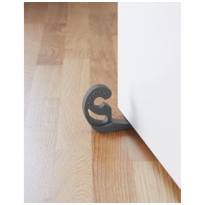 Il fermaporta Multi-Stop® antracite in plastica blocca una porta bianca su un pavimento in legno.