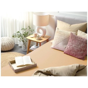 Lenzuolo con angoli Janbu in cotone beige sabbia 140x200 cm su un letto con cuscini e decorazioni.