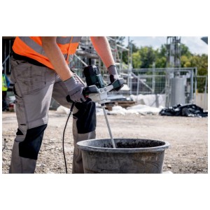 Arbeiter mischt Mörtel mit grünem Metabo Rührwerk RWE 1200 R in schwarzem Eimer auf Baustelle.