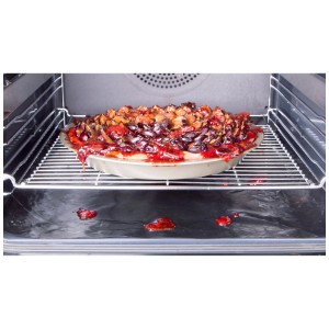 Tapis de protection de four noir sous le gâteau dans le four, ustensile de cuisine pour un four propre.