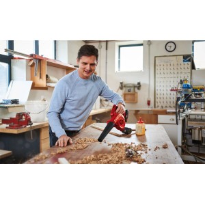 Uomo che utilizza il soffiatore a batteria Einhell TE-CB 18/180 Li-Solo per pulire trucioli di legno da un banco da lavoro.