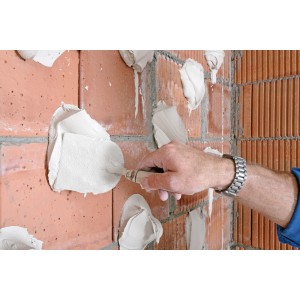 Applicazione di gesso adesivo Knauf Perlfix su una parete di mattoni con una cazzuola.