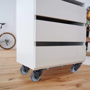 Wagner Transporthilfe Extender sous une armoire blanche à tiroirs sur un plancher en bois.